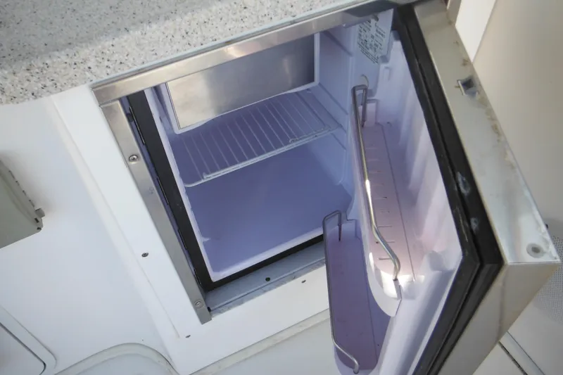 Slide: The Image of Open mini fridge inside 2000 Rinker 330 Fiesta Vee boat, showing interior shelving. - 27