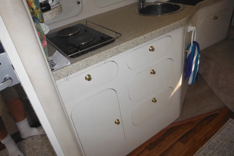 Slide: The Image of Compact kitchen area in a 2000 Rinker 330 Fiesta Vee boat, featuring a stove and sink. - 43