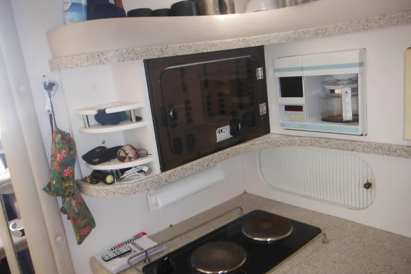 Slide: The Image of 2000 Rinker 330 Fiesta Vee kitchen with stove, microwave, and storage shelves. - 46