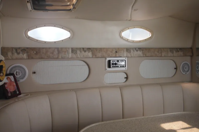 Slide: The Image of Interior of 2000 Rinker 330 Fiesta Vee boat with beige seating and oval windows. - 51