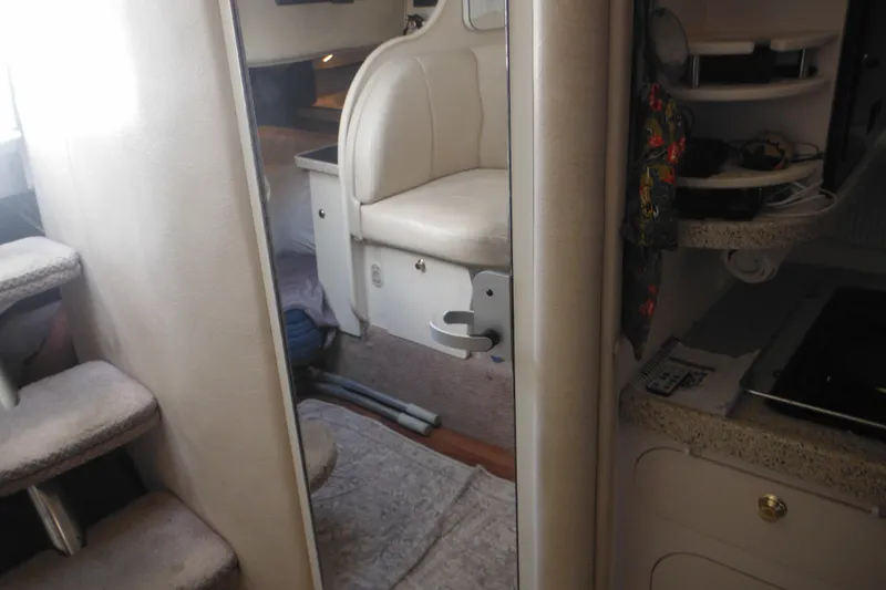 Slide: The Image of Interior of 2000 Rinker 330 Fiesta Vee boat, featuring seating and compact kitchen area. - 52