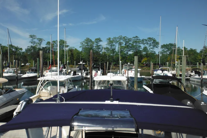 Slide: The Image of Marina with various boats, including a 2000 Rinker 330 Fiesta Vee, under a clear blue sky. - 68
