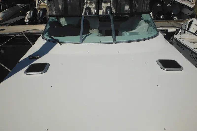 Slide: The Image of 2000 Rinker 330 Fiesta Vee boat docked, showcasing windshield and deck details. - 73