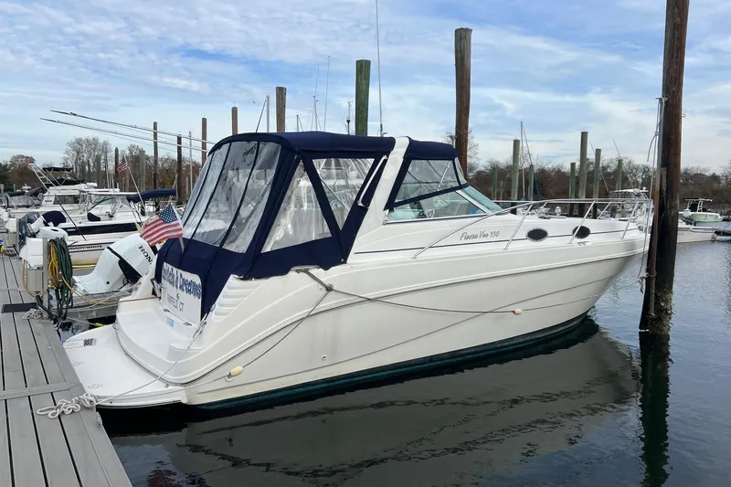 Slide: The Image of 2000 Rinker 330 Fiesta Vee boat docked at marina, featuring blue canopy. - 76
