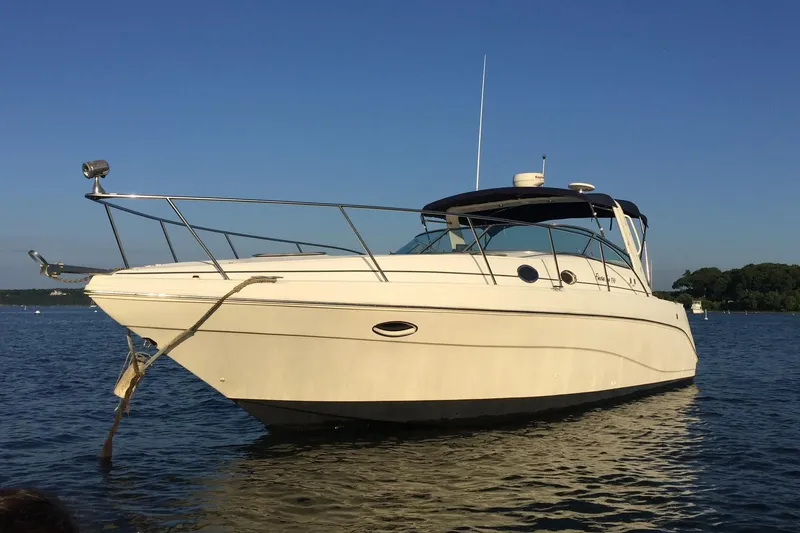 Slide: The Image of 2000 Rinker 330 Fiesta Vee boat anchored on calm water under clear blue sky. - 79