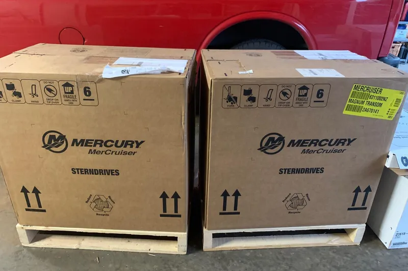 Slide: The Image of Cardboard boxes labeled "Mercury MerCruiser Sterndrives" beside a red vehicle. - 82