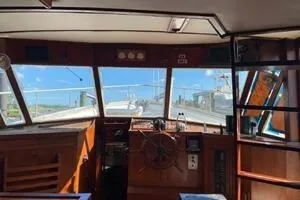 Slide: The Image of 1982 Mainship Trawler interior with wooden helm and panoramic windows. - 10