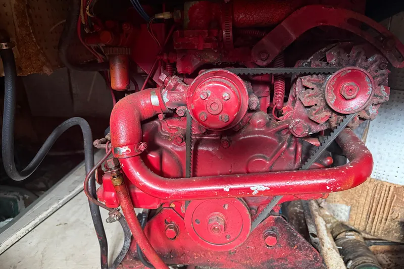 Slide: The Image of Red engine of a 1982 Albin 49 Trawler, showcasing mechanical components and belts. - 19