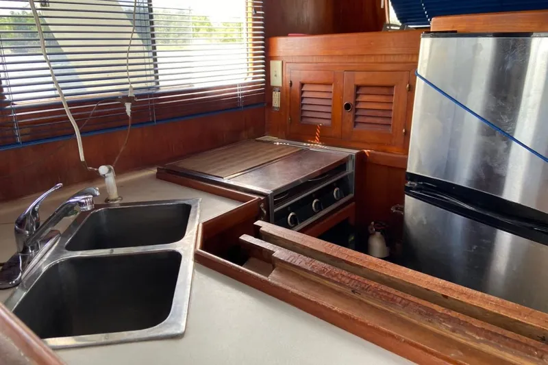 Slide: The Image of 1982 Albin 49 Trawler kitchen with stainless steel appliances and wooden cabinetry. - 24