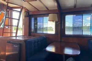 Slide: The Image of 1982 Mainship Trawler interior with wooden dining area and large windows. - 26