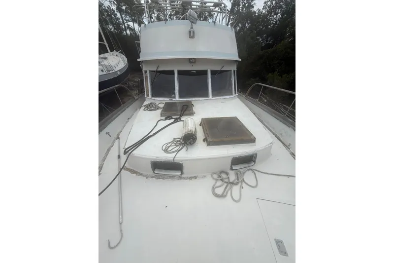 Slide: The Image of 1982 Albin 49 Trawler deck with ropes and hatches, surrounded by trees. - 43