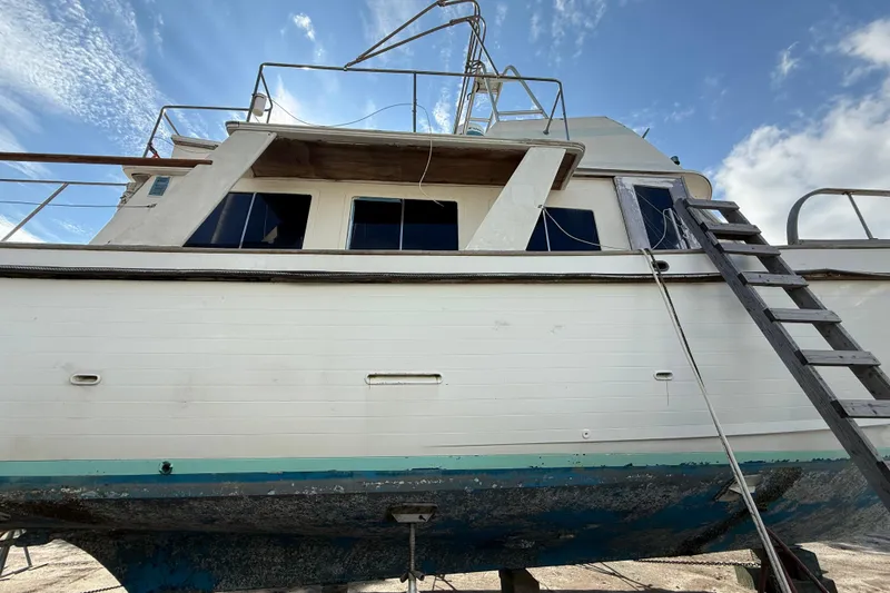 Slide: The Image of 1982 Albin 49 Trawler on dry dock, showing weathered hull and ladder under a blue sky. - 5