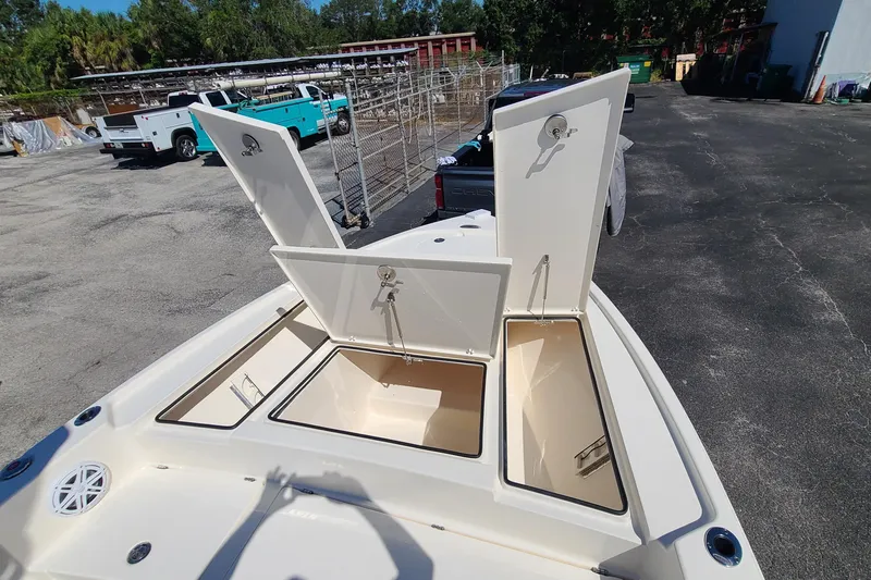 Slide: The Image of 2023 Pathfinder 2500 Hybrid boat with open storage compartments in a parking area. - 12