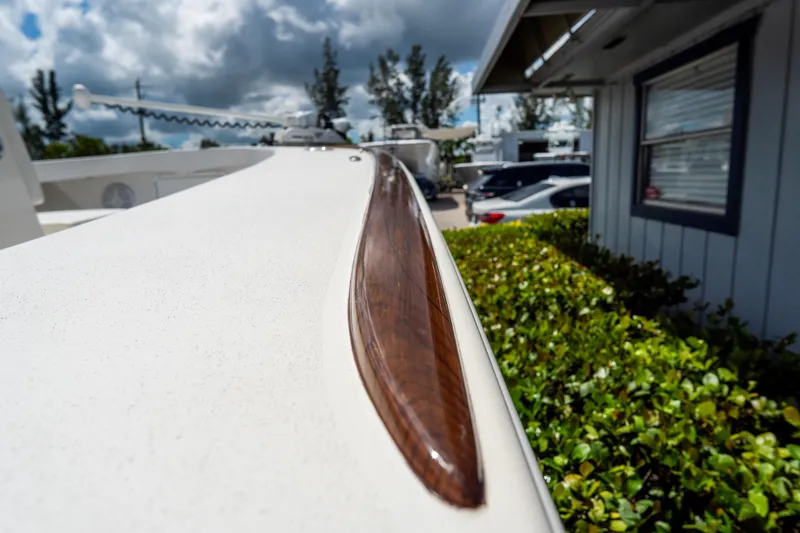 Slide: The Image of 2022 Croswait Custom Carolina 21 boat detail with wooden trim, under cloudy sky. - 31