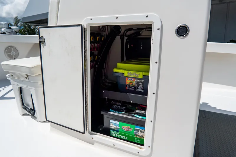Slide: The Image of Open storage compartment on 2022 Croswait Custom Carolina 21 boat, showing batteries and supplies. - 36
