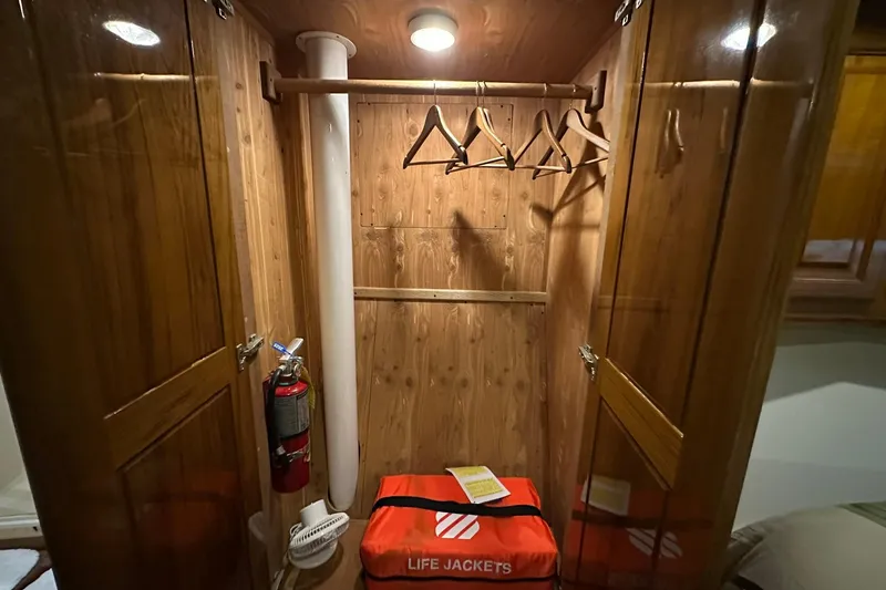 Slide: The Image of Wooden closet interior on a 1998 Viking 54 Motor Yacht with life jackets and hangers. - 40