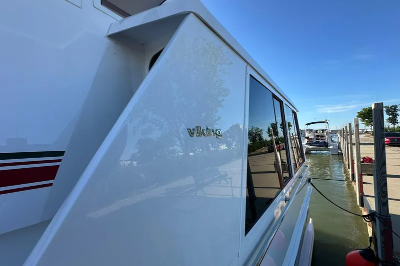 Slide: The Image of 1998 Viking 54 Motor Yacht docked, reflecting clear blue sky and trees. - 5