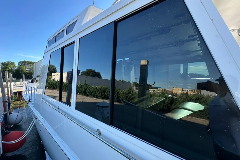 Slide: The Image of 1998 Viking 54 Motor Yacht docked, reflecting clear blue sky and surrounding greenery. - 7