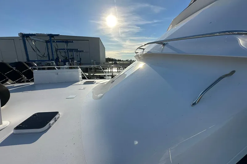 Slide: The Image of 1998 Viking 54 Motor Yacht deck under bright sun, near a marina building. - 8