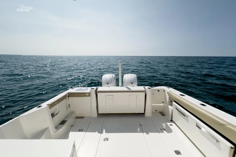 Slide: The Image of 2021 Pursuit DC 326 Dual Console boat on open sea, showcasing spacious deck and twin engines. - 11