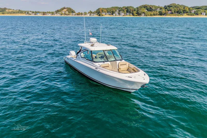 Slide: The Image of 2021 Pursuit DC 326 Dual Console boat on open water near a scenic shoreline. - 3