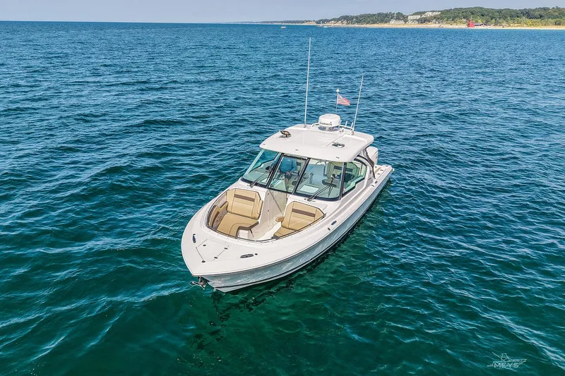 Slide: The Image of 2021 Pursuit DC 326 Dual Console boat on open water, clear sky, distant shoreline. - 4