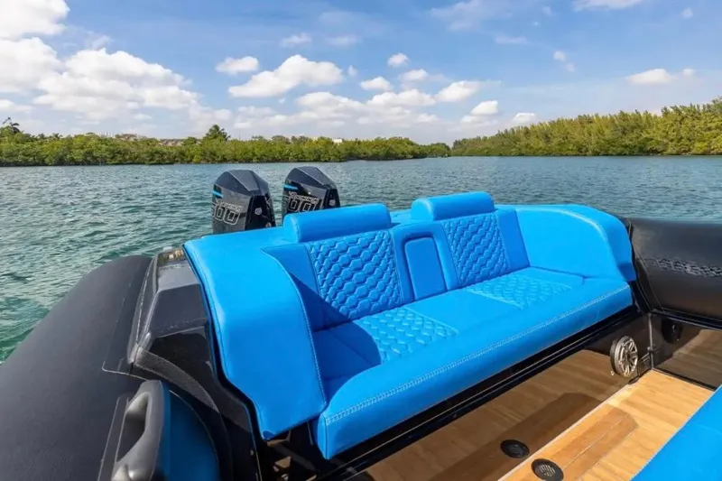 Slide: The Image of 2025 Technohull 38 Gran boat with blue seating, on a serene waterway. - 12