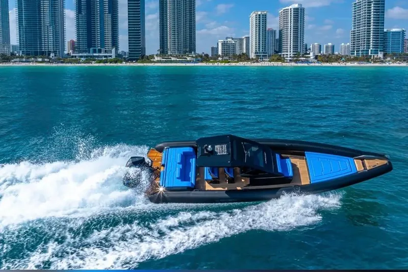 Slide: The Image of 2025 Technohull 38 Gran speedboat cruising near city skyline on blue ocean waters. - 2