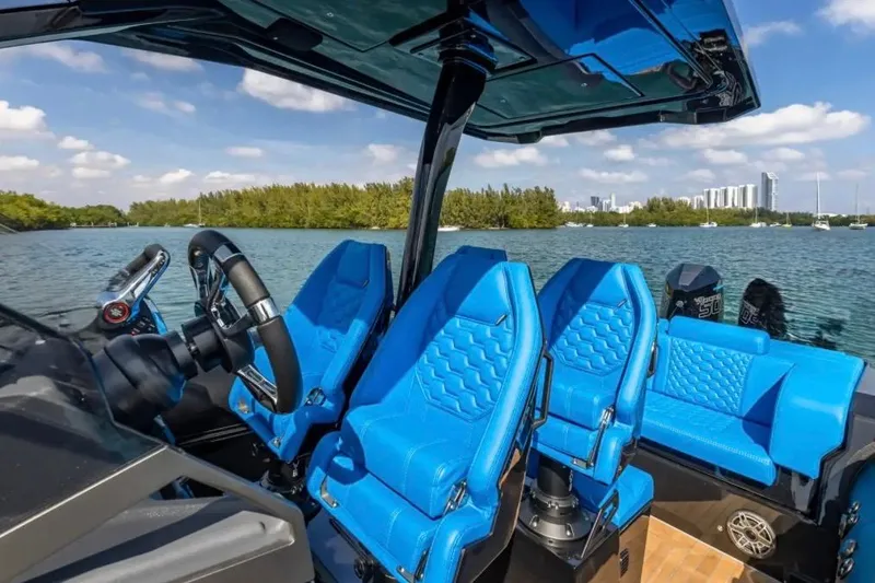 Slide: The Image of 2025 Technohull 38 Gran boat interior with blue seats, steering wheel, and scenic water view. - 23