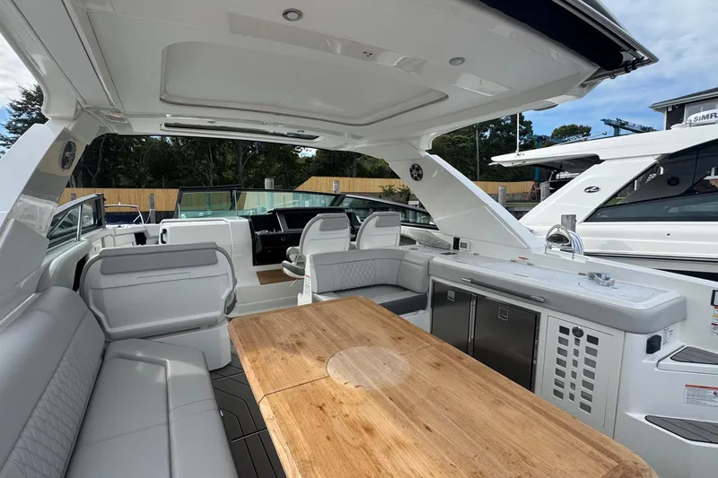 Slide: The Image of 2025 Sea Ray SLX 400 Outboard interior with seating, table, and kitchenette. - 19