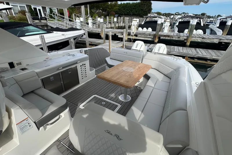 Slide: The Image of 2025 Sea Ray SLX 400 Outboard luxury boat interior with seating and table at marina. - 21