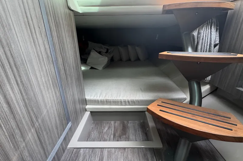 Slide: The Image of 2025 Sea Ray SLX 400 Outboard cabin interior with wooden steps and cozy bedding. - 40