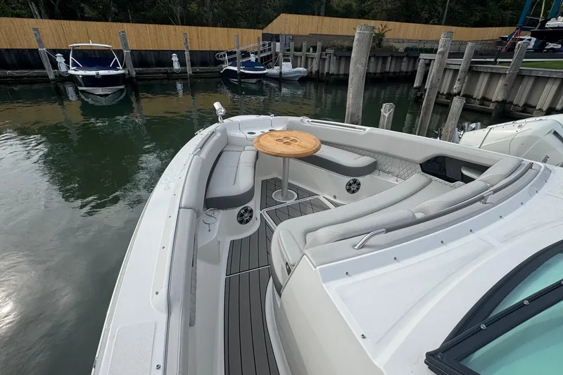 Slide: The Image of 2025 Sea Ray SLX 400 Outboard boat with spacious seating and wooden table in a marina. - 44