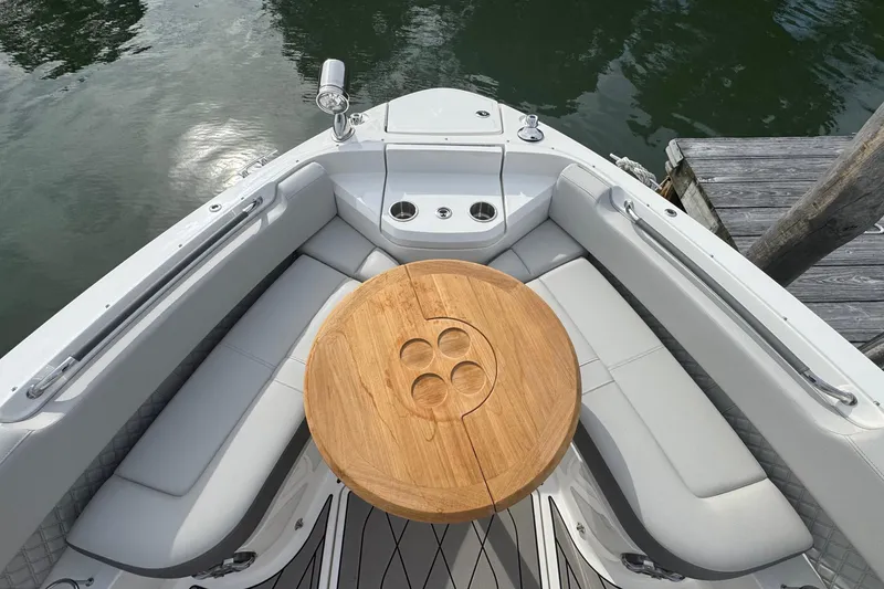 Slide: The Image of 2025 Sea Ray SLX 400 Outboard boat interior with wooden table and cushioned seating. - 47