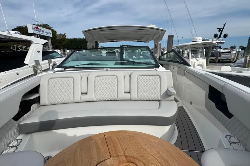 Slide: The Image of 2025 Sea Ray SLX 400 Outboard luxury boat interior with plush seating and wooden table. - 50