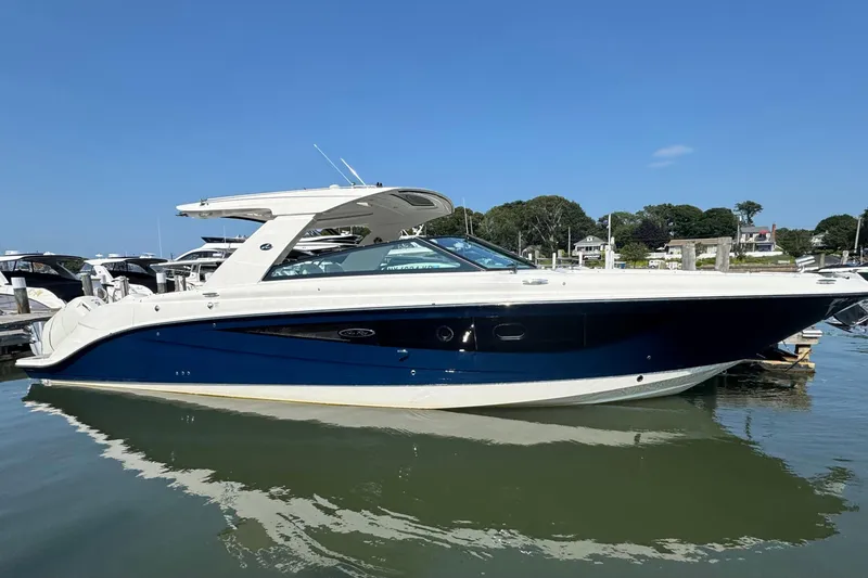 Slide: The Image of 2025 Sea Ray SLX 400 Outboard boat docked in a marina under clear blue skies. - 7