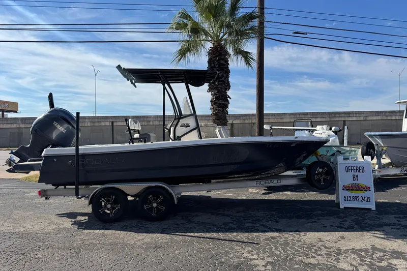 The Image of 2023 Robalo 206 Cayman boat on trailer, displayed outdoors with palm tree background. - 0