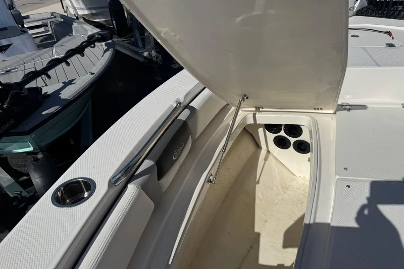 Slide: The Image of 2023 Robalo 206 Cayman boat storage compartment with open hatch and cup holder. - 31