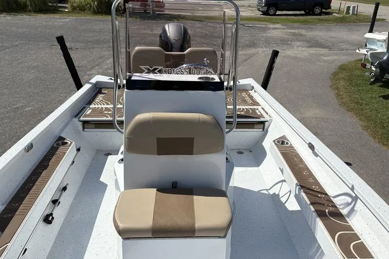 Slide: The Image of 2022 Xpress H22B Bay boat interior with tan seating and console, parked on pavement. - 19