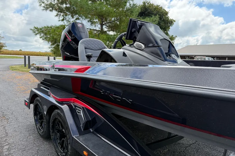 Slide: The Image of 2026 iKon LXE21 boat with sleek design, parked outdoors under cloudy sky. - 8