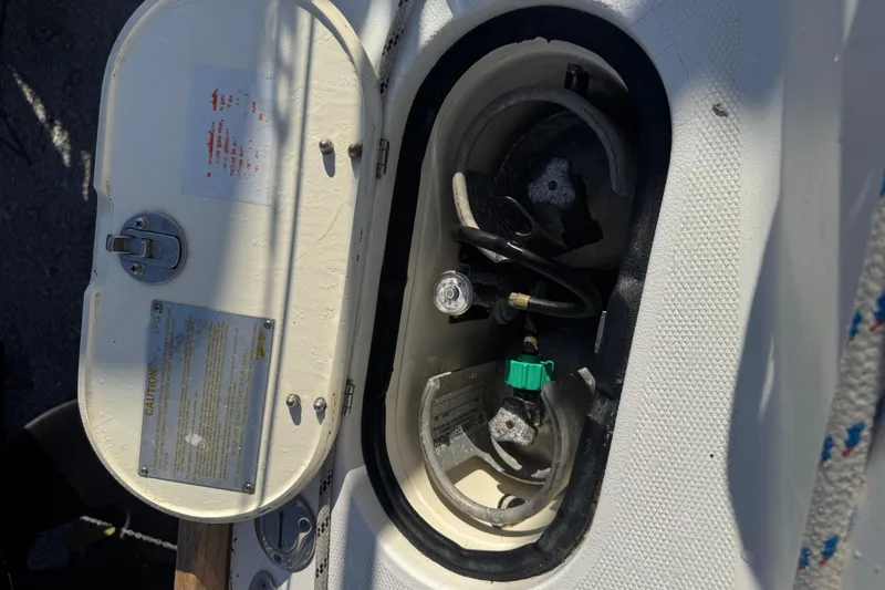 Slide: The Image of Open storage compartment on a 2005 Sabre 386 boat, showing gas connections and safety labels. - 32