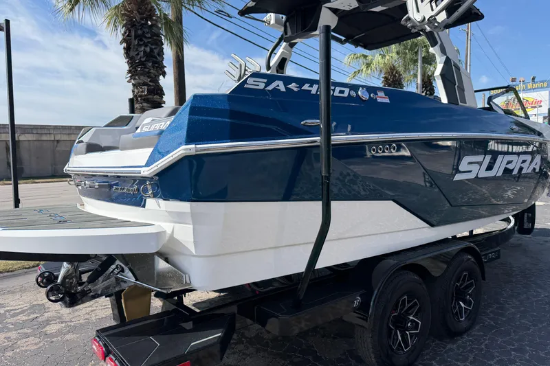 Slide: The Image of 2026 Supra SA 450 boat on trailer, blue and white design, parked outdoors. - 11