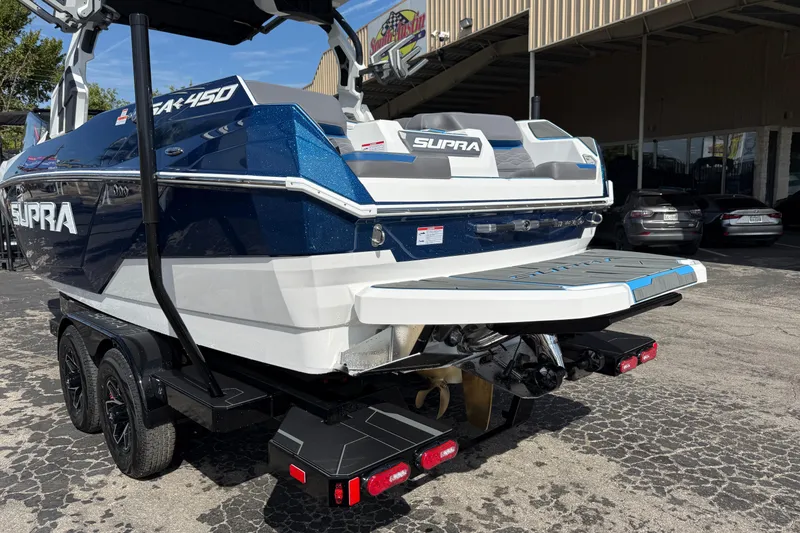 Slide: The Image of 2026 Supra SA 450 boat on trailer, blue and white design, parked outdoors. - 7
