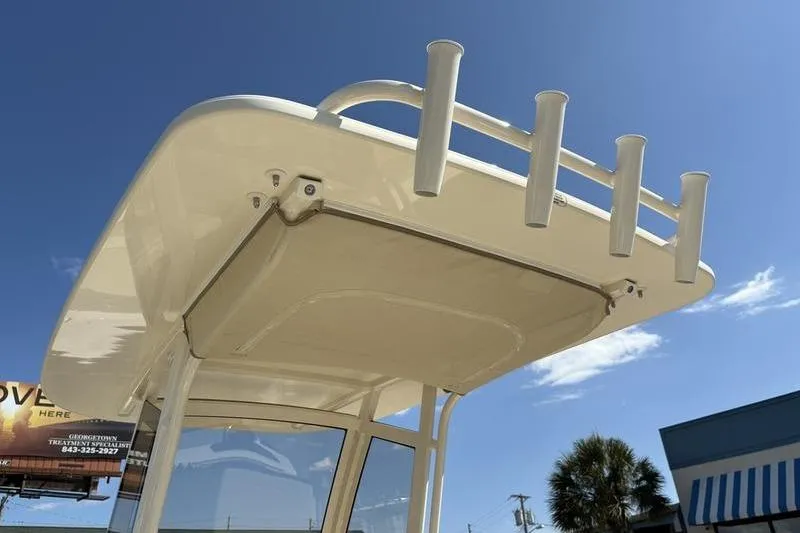 Slide: The Image of 2026 Scout 240 XSF boat top with rod holders under clear blue sky. - 16