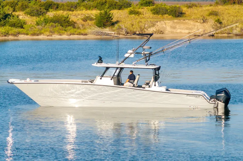 Slide: The Image of 2022 Freeman 42 LR boat on calm water with fishing rods, scenic background. - 0