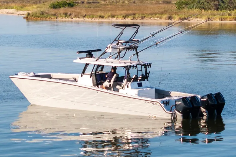 Slide: The Image of 2022 Freeman 42 LR boat on calm water, equipped with multiple fishing rods. - 1