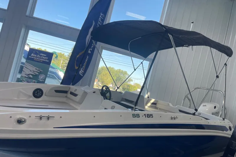 Slide: The Image of 2023 Hurricane SunDeck Sport 185 OB boat with canopy, displayed indoors. - 22