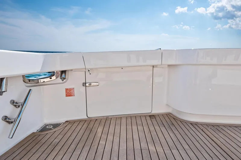 Slide: The Image of 2017 Viking 62 Enclosed Bridge yacht deck with sleek white finish and wooden flooring. - 21