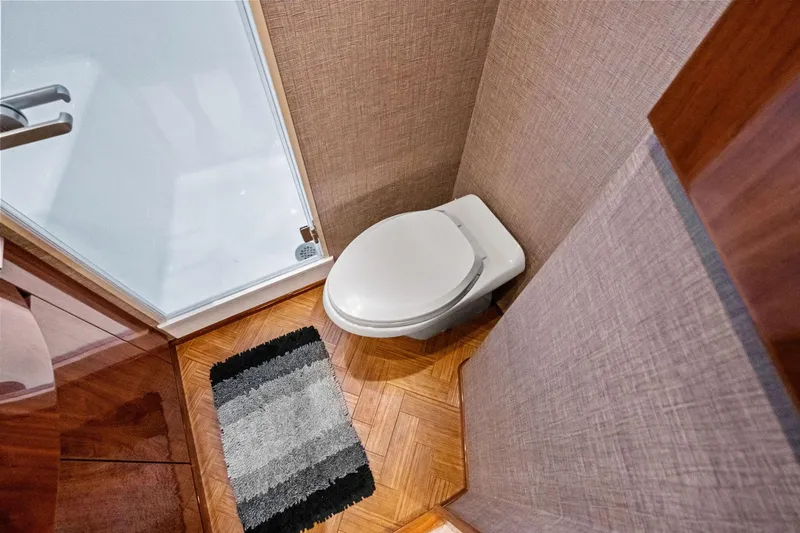 Slide: The Image of 2017 Viking 62 Enclosed Bridge bathroom with toilet and shower, featuring wood flooring. - 38