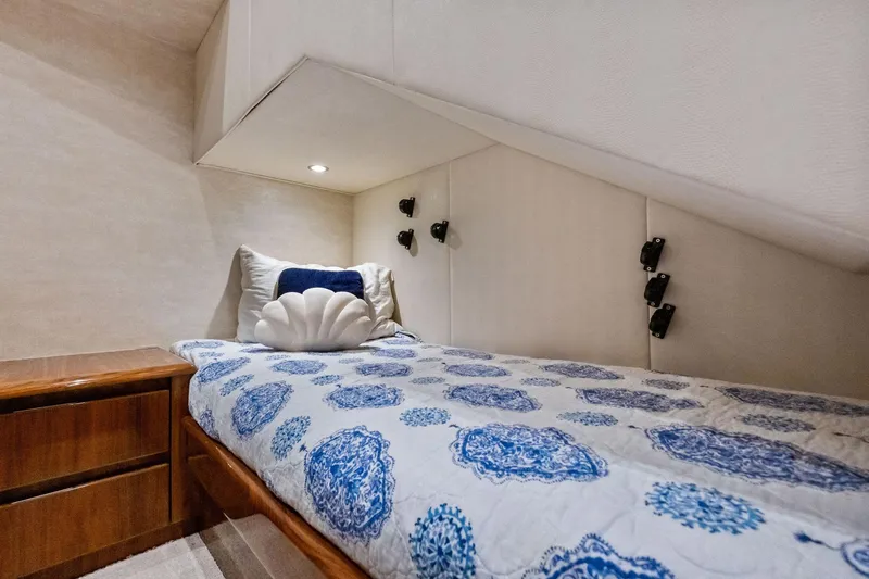 Slide: The Image of Cozy cabin interior of 2017 Viking 62 Enclosed Bridge with patterned bedding and wooden nightstand. - 46